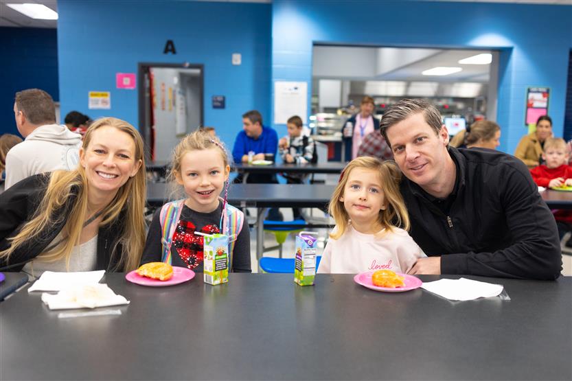 Creekside Elementary students eat donuts with a grown-up